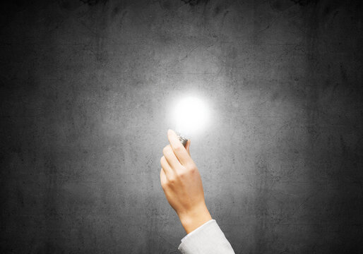 Woman hand holding glowing light bulb