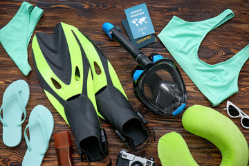 Female beach accessories with snorkeling mask and immune passport on dark wooden background