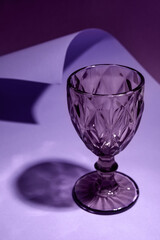 Stylish empty glass on purple  background, closeup