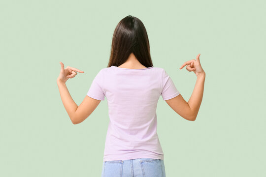 Pretty young woman in stylish t-shirt on green background, back view