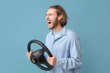 Angry man with steering wheel on blue background
