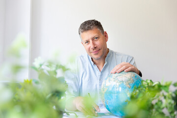 Business portrait of environmental engineer, ecologist, garden architect sitting at his work table...