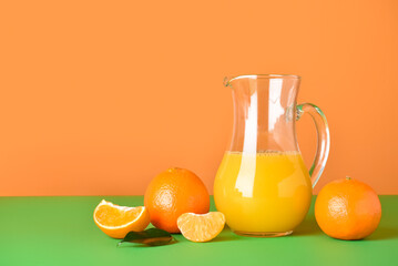 Jug of fresh tangerine juice on color background