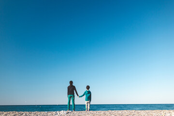 a boy and mother look at the sea