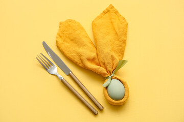 Stylish table setting for Easter celebration on yellow background