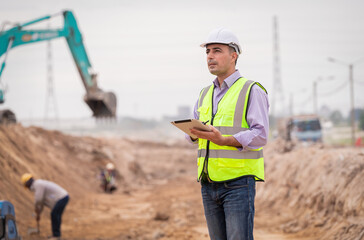 Surveyor engineer wearing safety uniform ,helmet and radio communication with equipment theodolite...