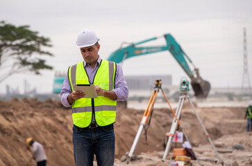 Surveyor engineer wearing safety uniform ,helmet and radio communication with equipment theodolite...