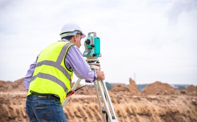 Surveyor engineer wearing safety uniform ,helmet and radio communication with equipment theodolite...