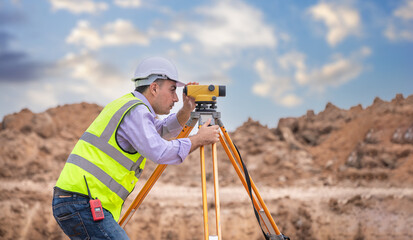 Surveyor engineer wearing safety uniform ,helmet and radio communication with equipment theodolite...