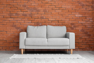 Stylish sofa near brick wall