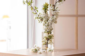 Vase with beautiful blooming tree branches on table in light room