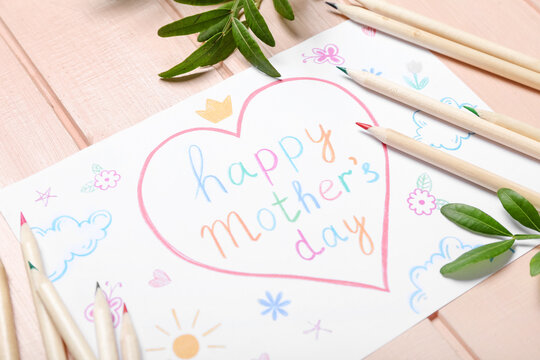 Card with text HAPPY MOTHER'S DAY, pencils and plant branches on pink wooden background, closeup