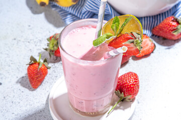One glass with Strawberry banana milkshake, with fresh fruits on white concrete table, copy space