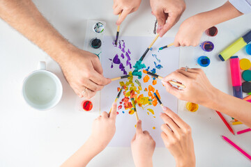Humans hand of mother father and children is drawing with colorful pencils. Top view to white table with art supplies. Kids art, creativity children concept.