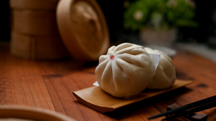 Delicious Chineses bao-zi or steamed pork buns on a wooden plate