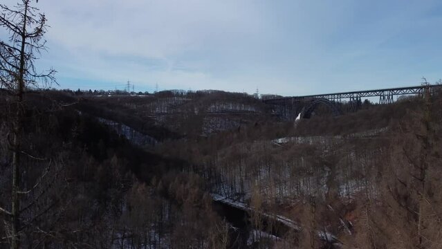 Drone fly between trees in winter to reveal scenery of rural area and the highest railway bridge in Germany.