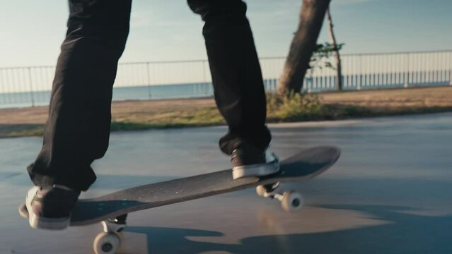 Skateboarding on Street. Cinematic close up of authentic and trendy skateboarder stroll through sunset filled california vibes promenade on warm summer evening. Outdoors activity