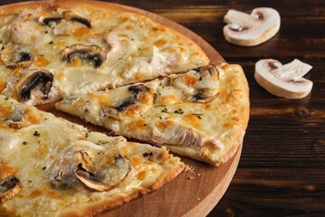Homemade Pizza with champignons and mozzarella cheese on a wooden background. Horizontal orientation, close-up, copy space, no people