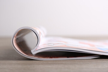 One open magazine on wooden table, closeup