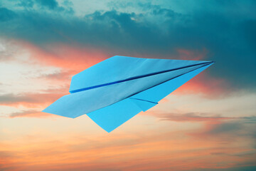 Light blue paper plane and view of beautiful sky at sunset