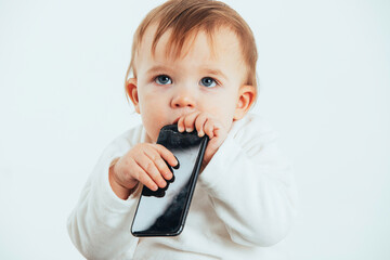 Studio photo with the white background of a baby's face with a mobile in his hands.