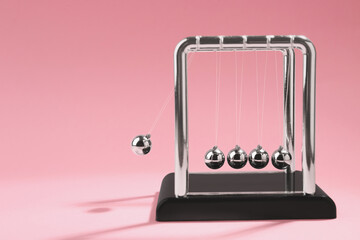Newton's cradle on pink background, space for text. Physics law of energy conservation