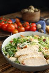 Delicious Caesar salad in bowl on wooden table, closeup