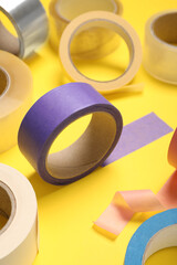 Many rolls of bright adhesive tape on yellow background