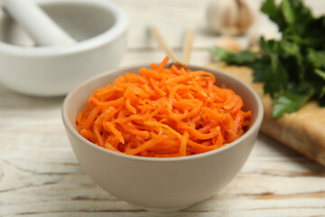 Delicious Korean carrot salad in bowl on white wooden table