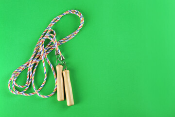 Skipping rope on green background, top view. Space for text