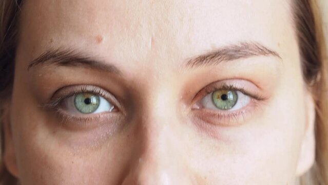 Face of a beautiful young woman with green eyes, puts on glasses, suffers from myopia