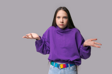 Portrait pretty surprised girl showing hand gesture dressed in purple sweatshirt and jeans....
