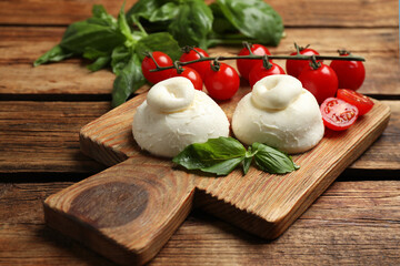 Delicious burrata cheese with basil and cherry tomatoes on wooden table