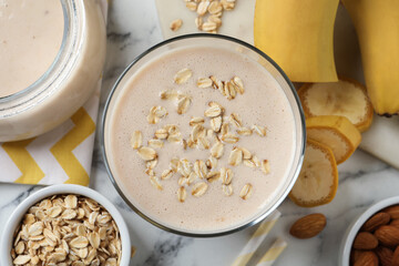 Glass of tasty banana smoothie with oatmeal on white marble table, flat lay