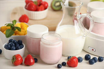 Portion jars for yogurt maker and different fruits on white wooden table