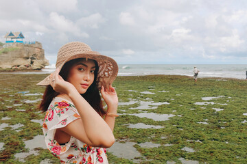 A young Asian girl wearing a beach hat is relaxing on the blue sky beach at Gunungkidul, Indonesia