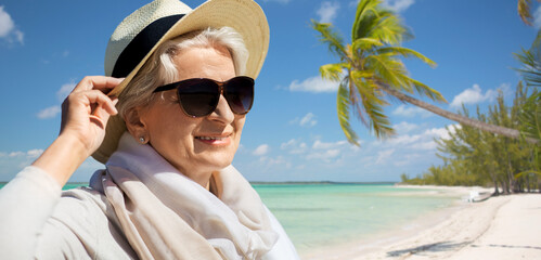 travel, tourism and summer vacation concept - portrait of happy senior woman in sunglasses and...