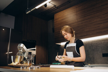 Pastry chef confectioner young caucasian woman with kitchen bowl on kitchen table. Cakes dessert making