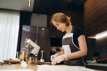 Pastry chef confectioner young caucasian woman with kitchen bowl on kitchen table. Cakes dessert making