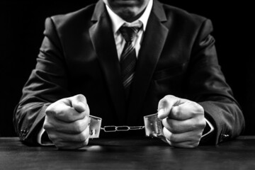 Arrested business man handcuffed hands on the black.Black and white