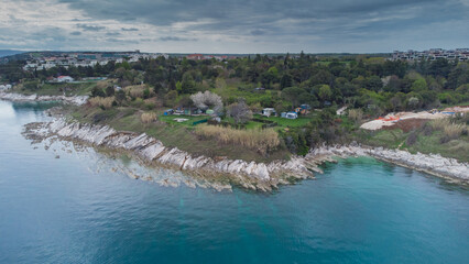 Rocky beach around Savudrija or Alberi area viewed from above. Drone view of visible rocks leading into the blue sea on a cloudy day. Typical istrian rock formations and wild camping behind.