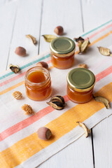 jam in several jars on a striped light-colored fabric decorated with dry leaves