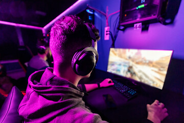 Back view of a gamer playing online game at gaming room.