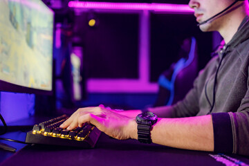 Close up of hands using keyboard for game at gaming room.