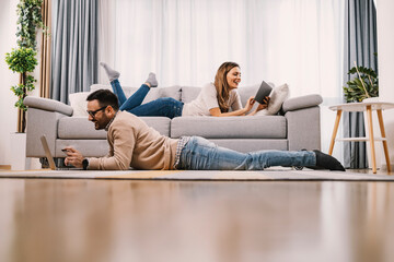 Happy couple entertaining themself with technologies at home.