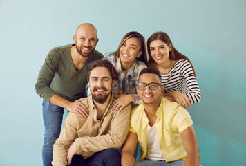 Portrait of smiling group of diverse multiracial young people on light blue background. Best...