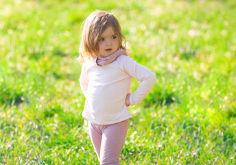 Baby girl walking in green grass. Child having fun on family picnic in summer garden.