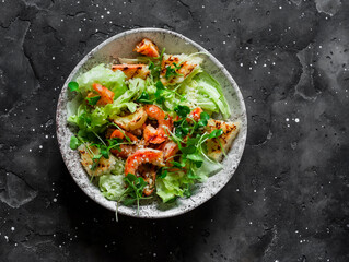 Caesar salad with grilled shrimp on a dark  background, top view