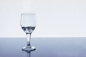 Wine glass with water and drops on the table, copy space