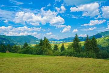mountain landscape. the glade is covered with grass on top of the mountains with blue skies and...